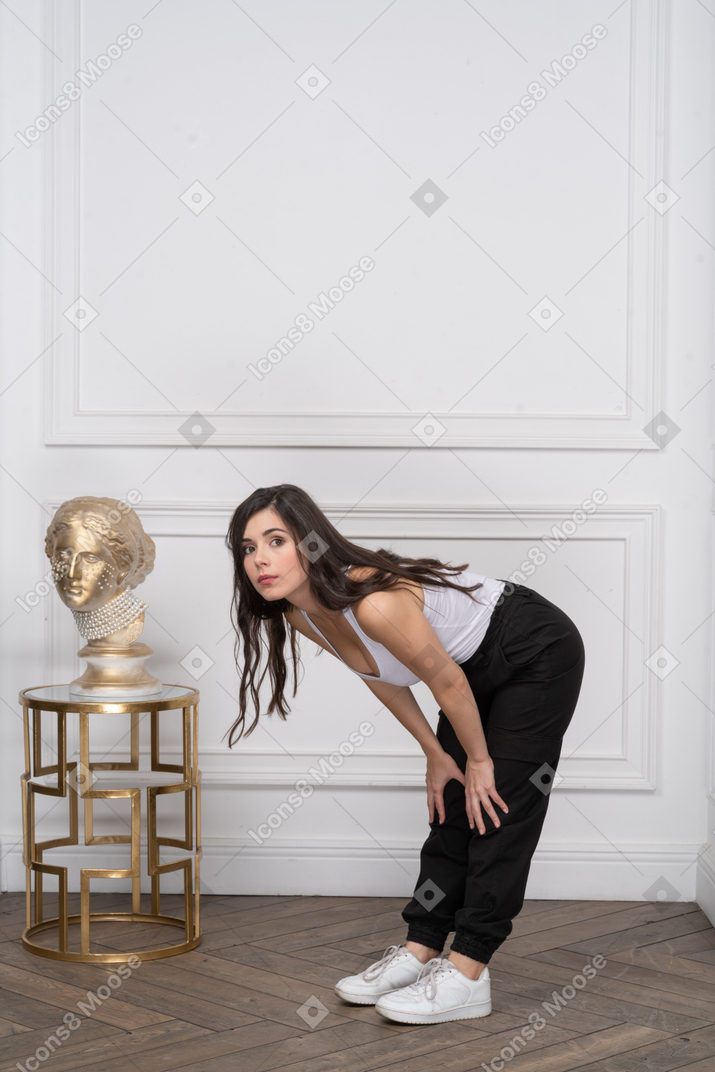 Young woman bending forward with hands on knees