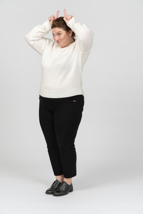 Vista frontale di una donna grassoccia in abiti casual che fa le corna