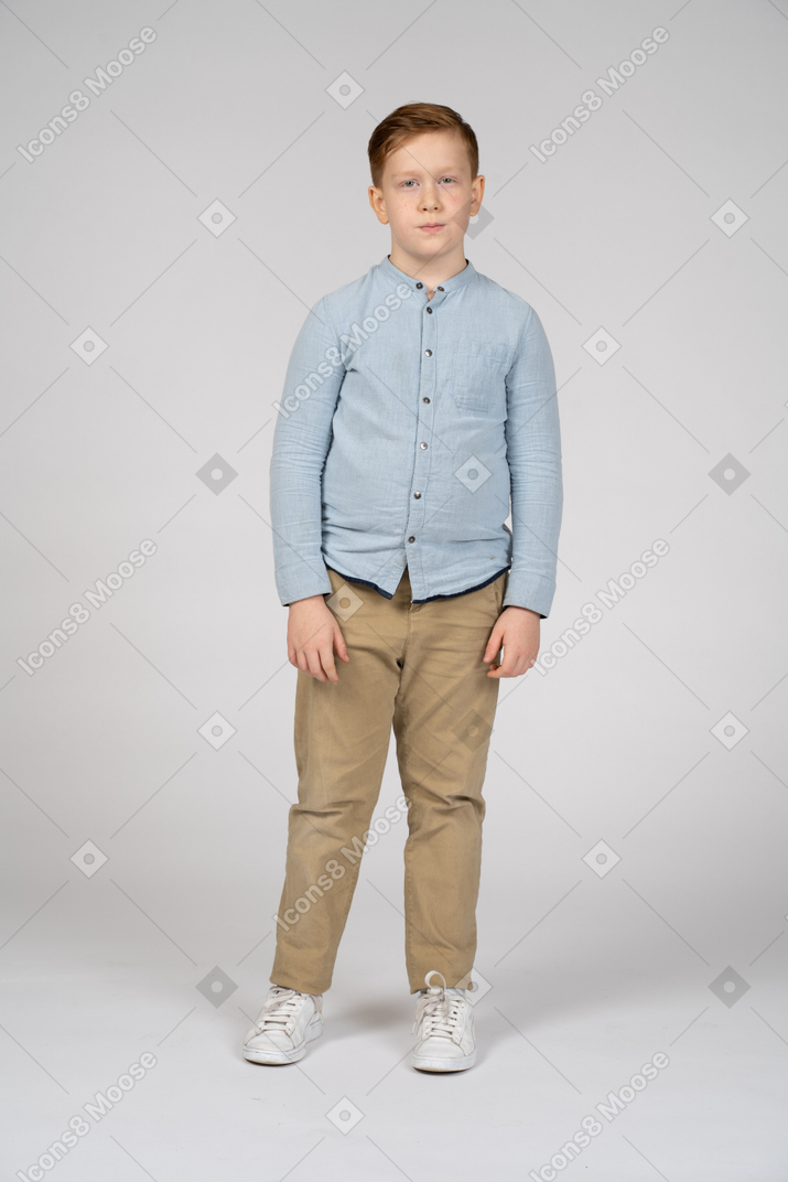 Вид спереди симпатичного мальчика в повседневной одежде, смотрящего в камеру