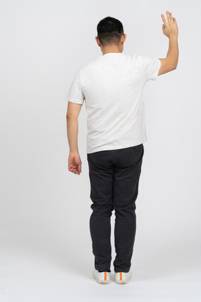 Back view of a man in casual clothes waving