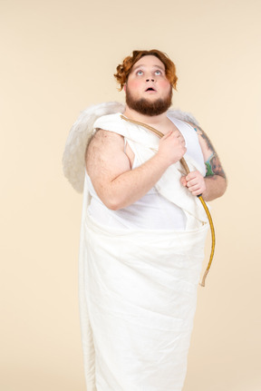 Big guy dressed as a cupid holding bow and looking up