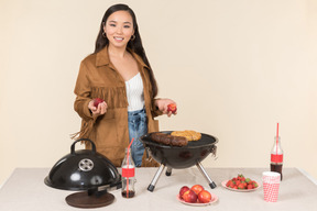 Jeune femme asiatique debout près de la table avec grill