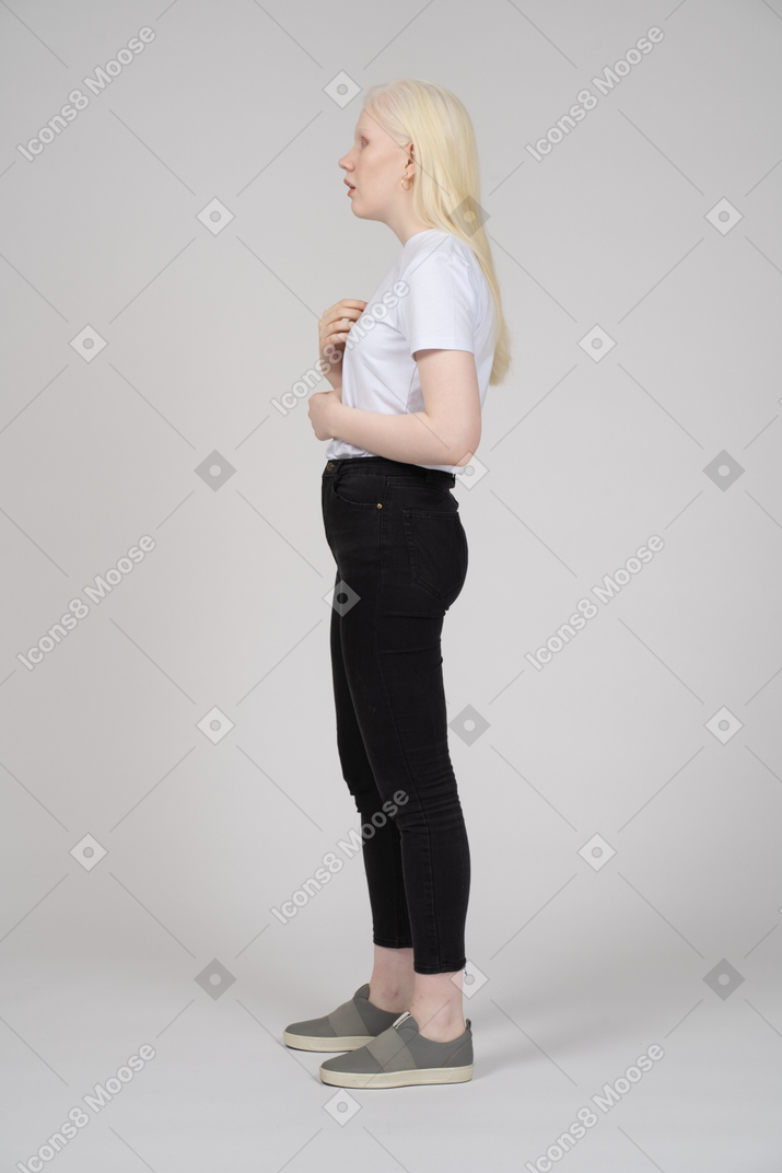 Profile view of a young woman in casual clothes pointing at herself