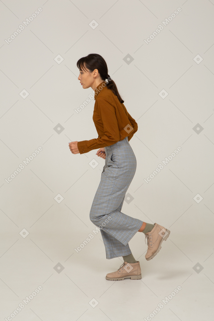 Side view of a running young asian female in breeches and blouse