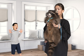 A woman holding a baby raccoon in a room