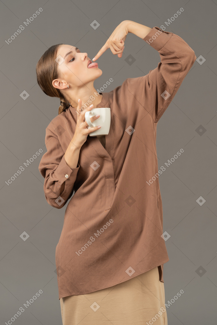 Senhora com xícara de café lambendo a ponta do dedo