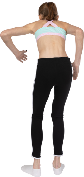 Vista posterior de una adolescente en ropa deportiva inclinada hacia adelante mientras está de pie como un robot