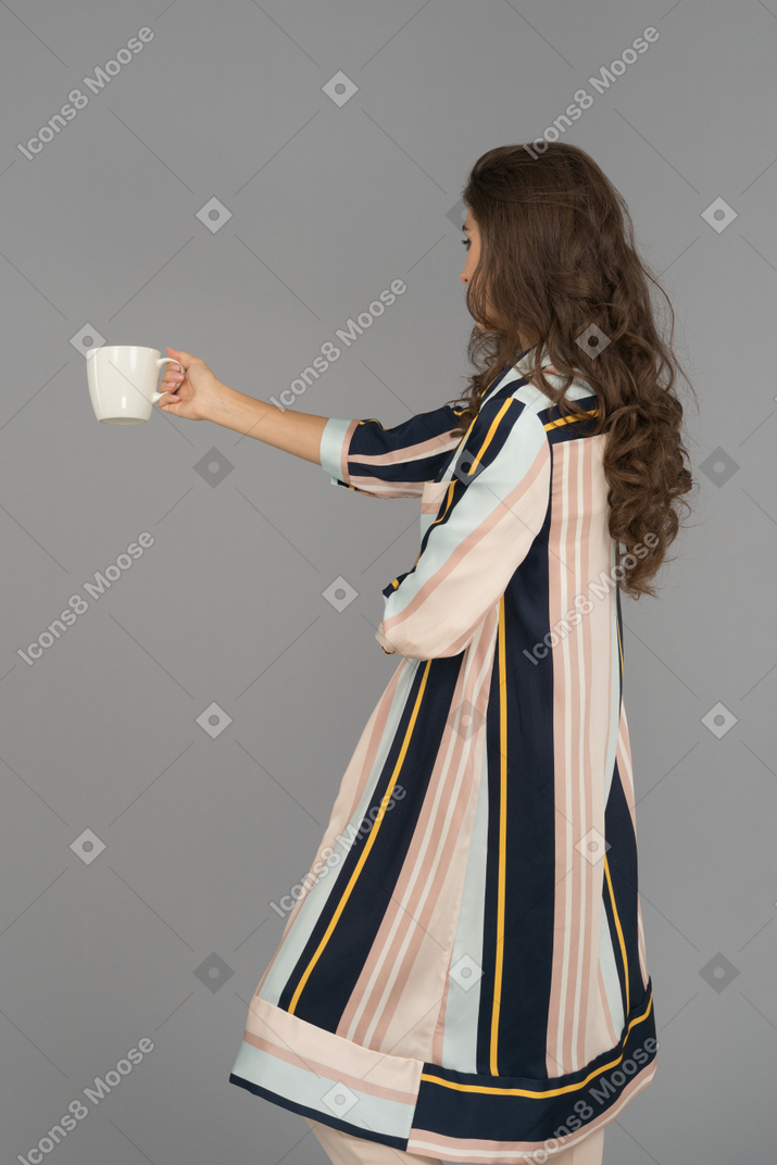 Young woman outstretching her one hand with a white cup