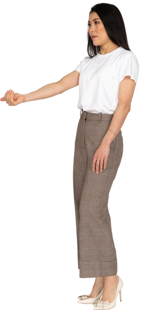 Вид в три четверти молодой леди в бриджах и футболке, протягивающей руку