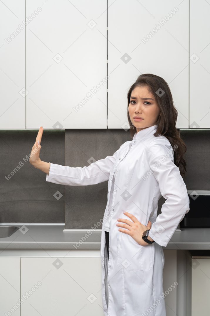 Side shot of a female doctor looking at camera outstretching her arm