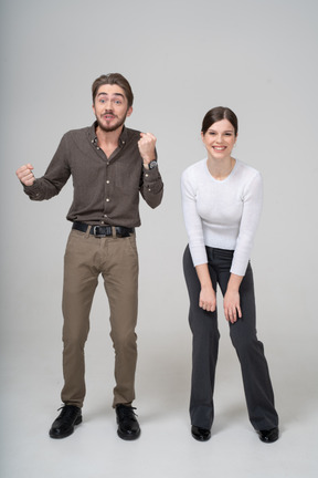 Front view of a delighted young woman and impatient man in office clothing