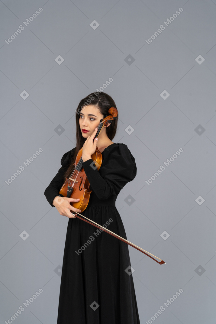 Primo piano di una giovane donna in abito nero che tiene il violino