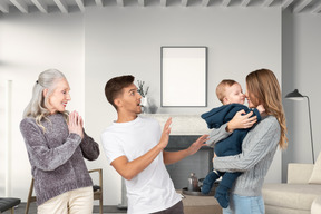 A woman holding a baby, a man and an old woman in a living room