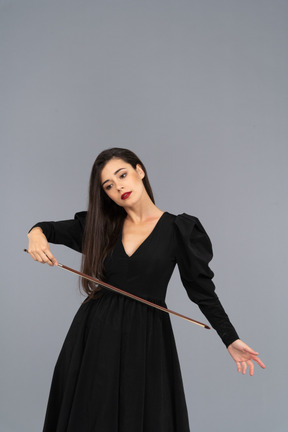 Vista frontal de uma jovem de vestido preto segurando o arco