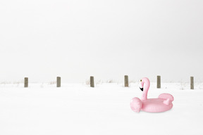 A pink inflatable flamingo sitting in the snow