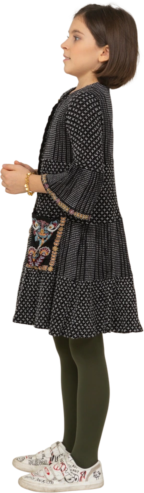 Side view of a confused little girl in dress holding hands together