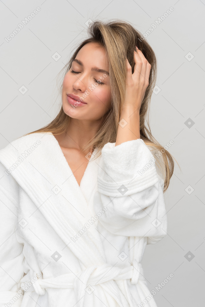 Young beautiful woman with closed eyes touching her hair
