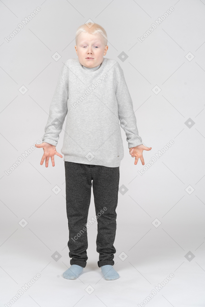 Small boy shrugging and looking down