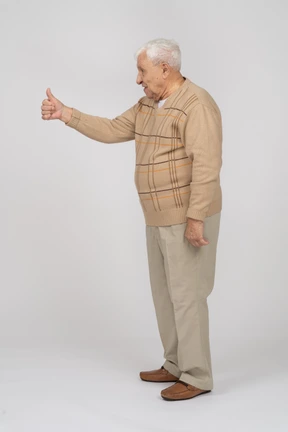 Side view of an old man in casual clothes showing thumb up