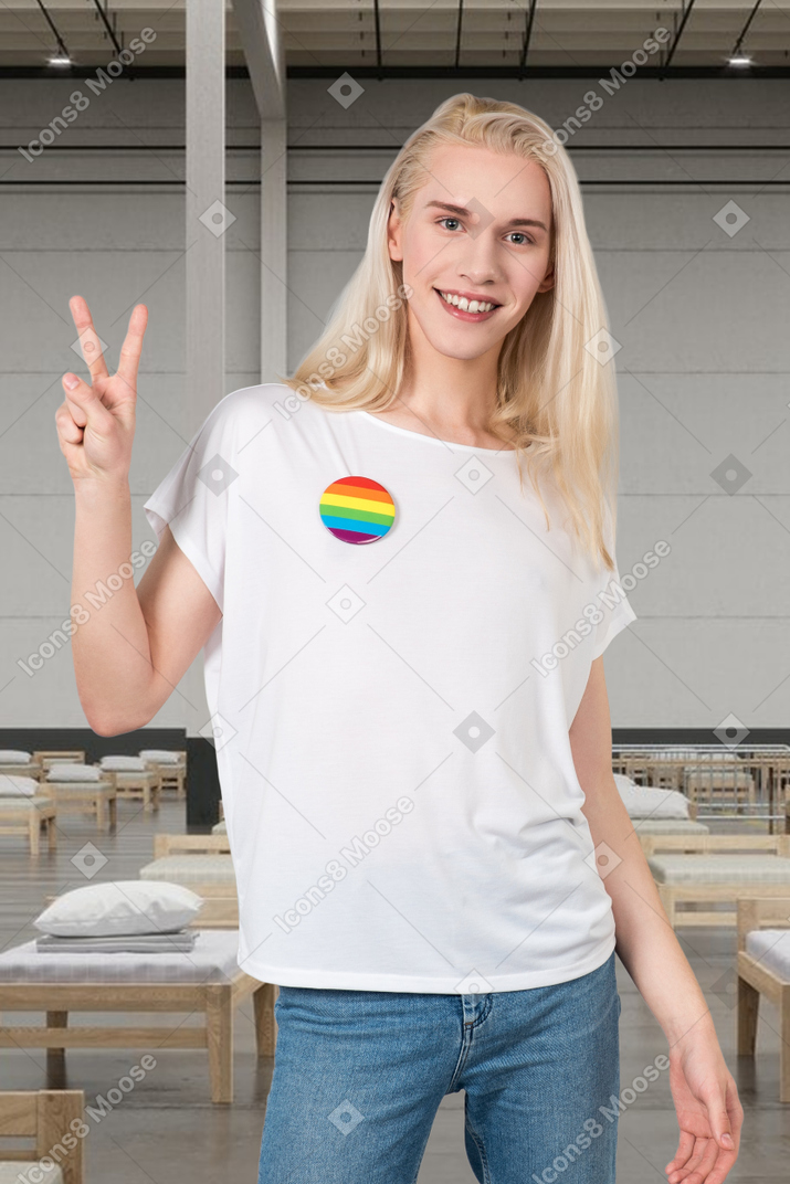 Person with a rainbow badge on their t-shirt showing a peace sign