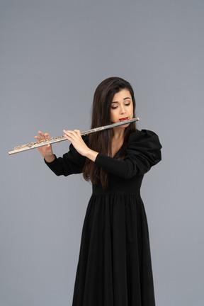 Front view of a serious young lady in black dress playing the flute