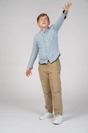 Vista frontal de un niño apuntando hacia arriba con la mano