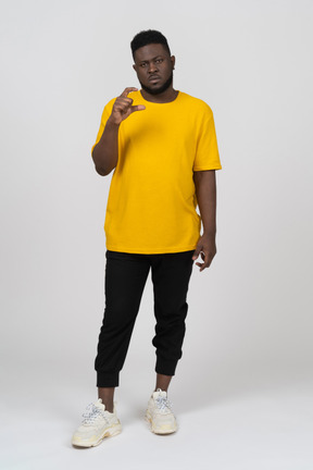 何かのサイズを示す黄色のtシャツを着た若い浅黒い肌の男の正面図