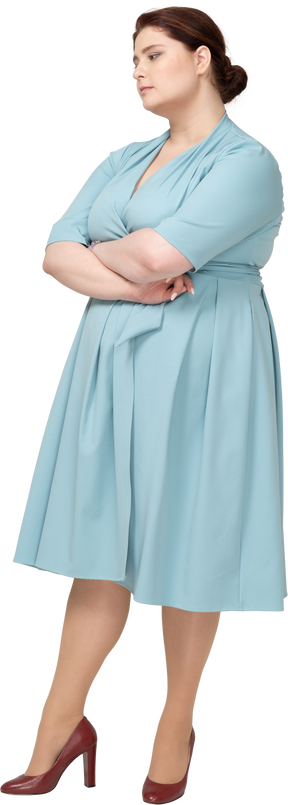 Vista frontal de uma mulher de vestido azul em pé com os braços cruzados