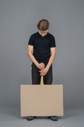 Depressed young man holding a poster upside down