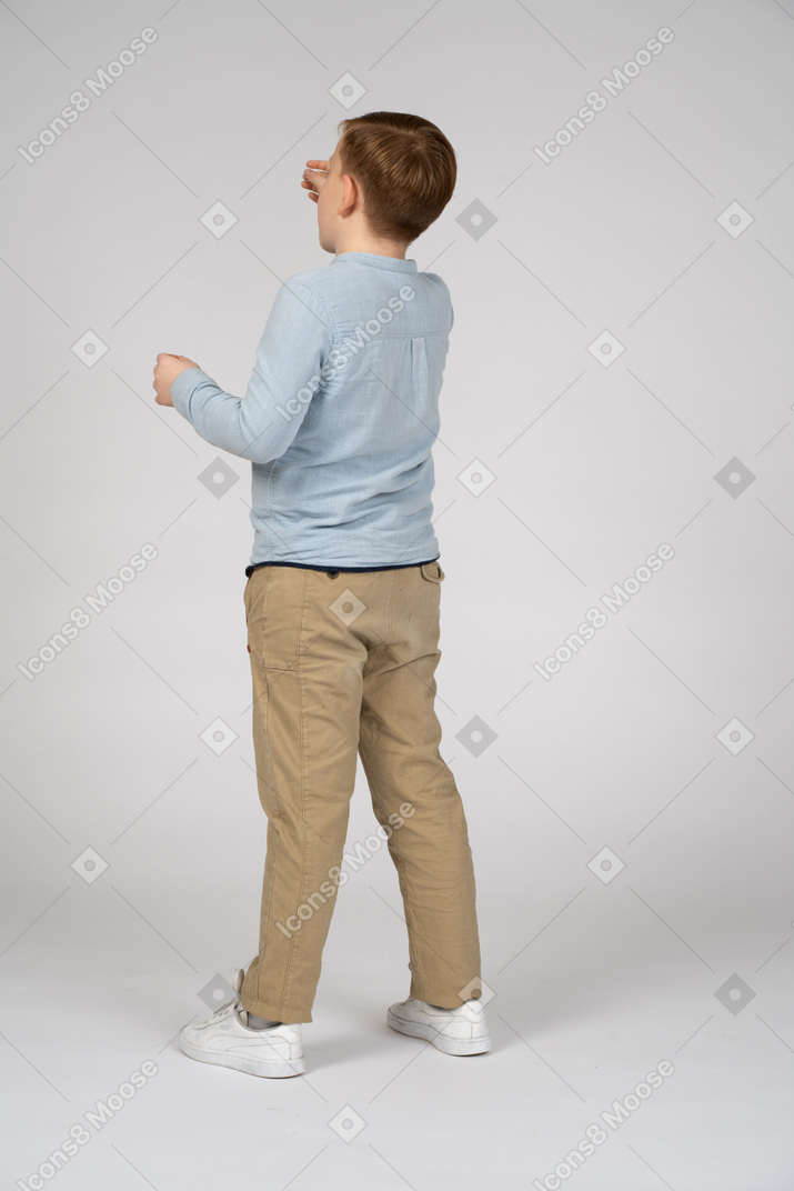 一个男孩站着伸手去拿东西的背影