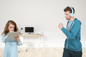 Shocked little girl looking at tablet screen and her dad going for a run