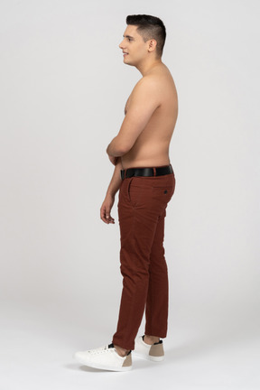 Vista lateral de un hombre latino sin camisa mirando tímido