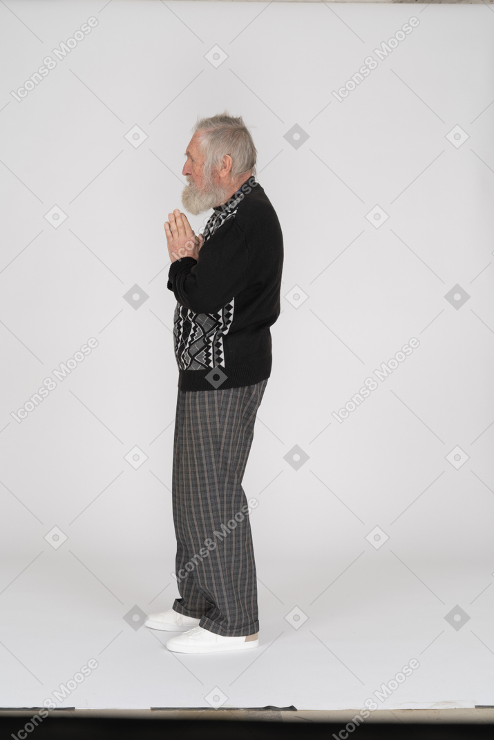 Side view of an old man folding his hands in prayer