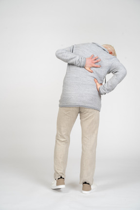Back view of a man standing and holding his hands on back