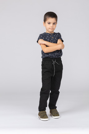 Vista frontal de un chico lindo posando con los brazos cruzados y mirando a la cámara