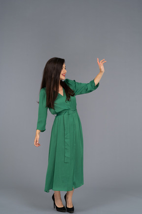 緑のドレスを着た挨拶の若い女性の4分の3のビュー