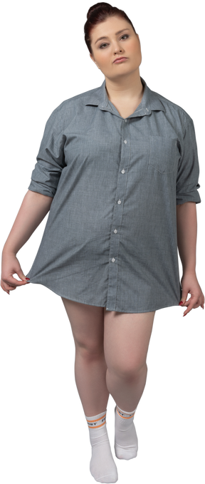 Mujer de talla grande posando en camisa de gran tamaño sobre el fondo gris