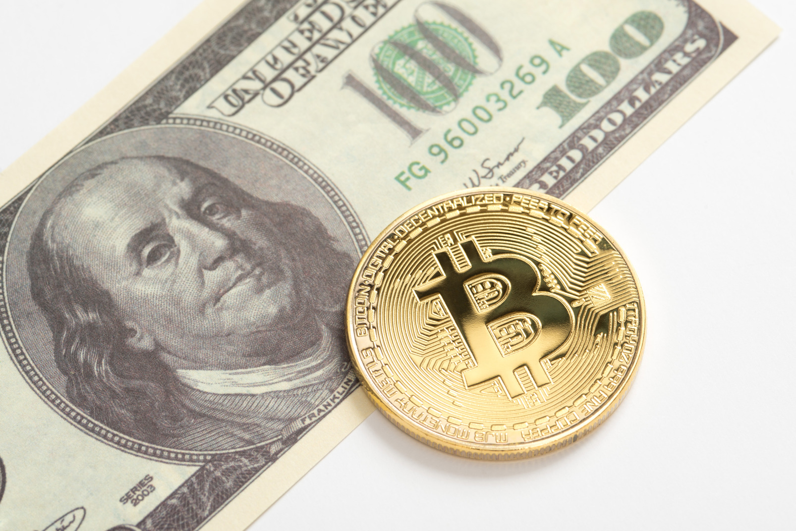 Golden bitcoin and one hundred dollar banknote