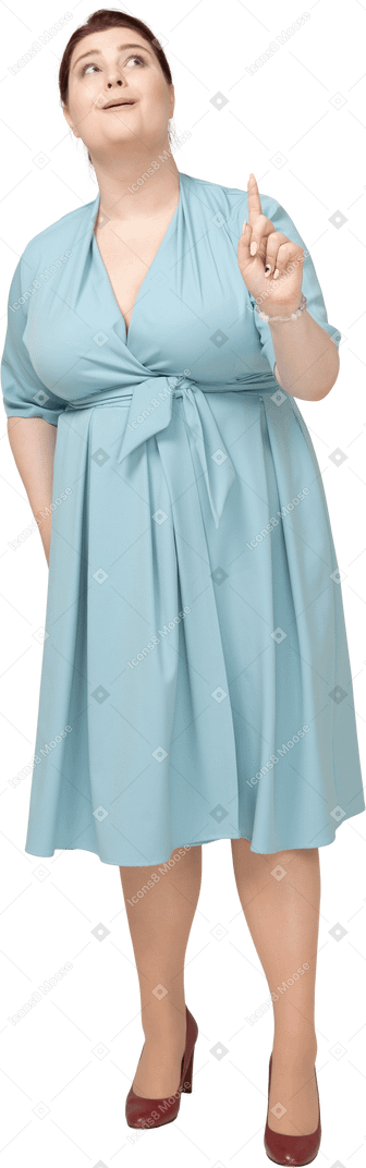 Vista frontal de uma mulher de vestido azul apontando para cima com um dedo