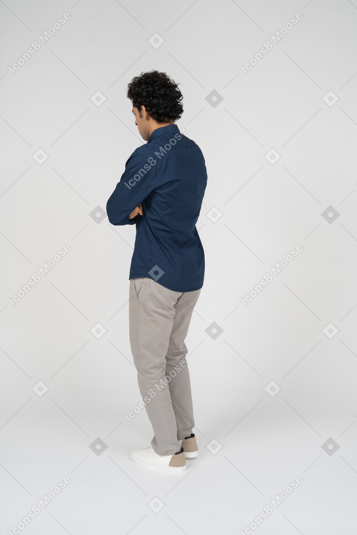 Vista laterale di un uomo in abiti casual in piedi con le braccia incrociate