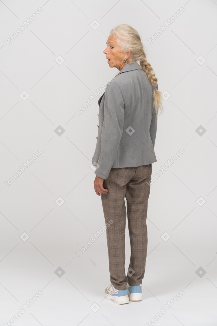 Вид сзади впечатленной старухи в сером пиджаке
