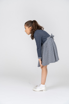 Vista lateral de una niña encorvada y agarrándose las rodillas