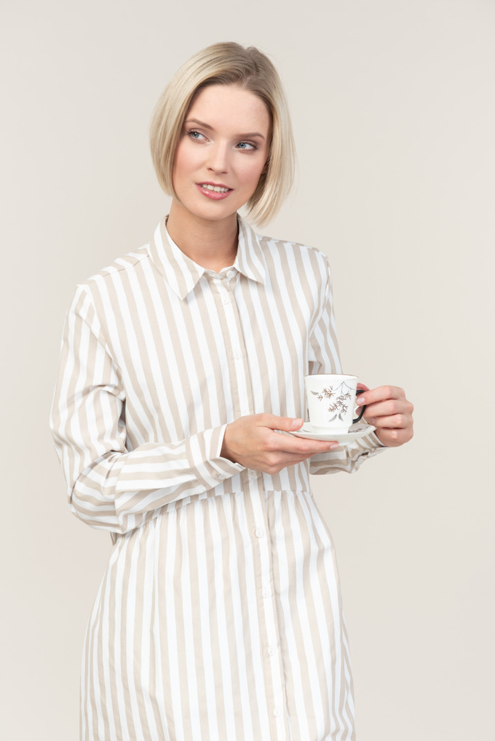 Pensive young woman holding cup of tea