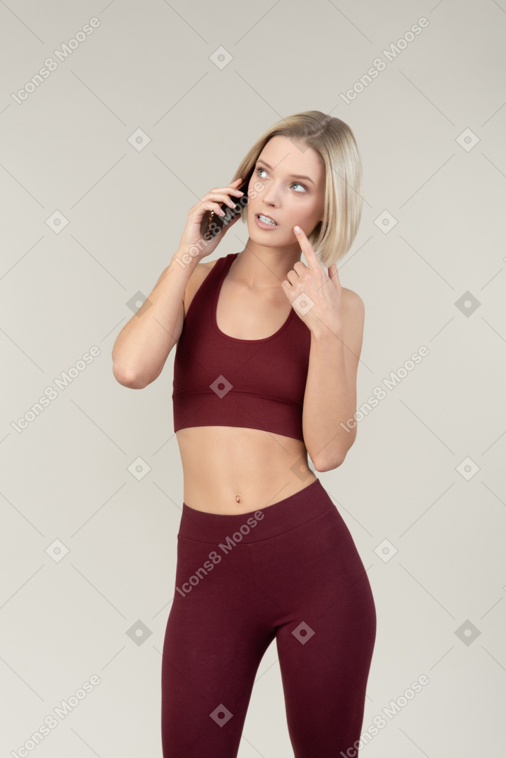 Jovem mulher pensativa falando ao telefone