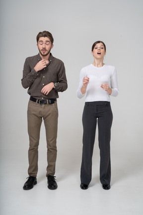 Front view of a sneezing young couple in office clothing