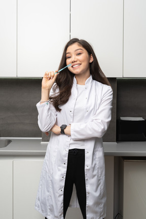 Front view of a female dentist holding a toothbrush and cheerfully looking at camera