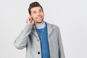 Handsome young guy adjusting earphones and looking up