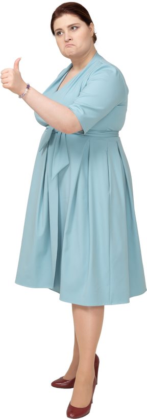 Вид сбоку женщины в синем платье показывает палец вверх