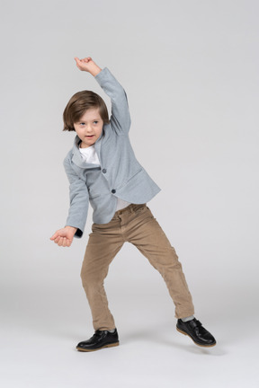 Boy in gray jacket and khaki pants dancing