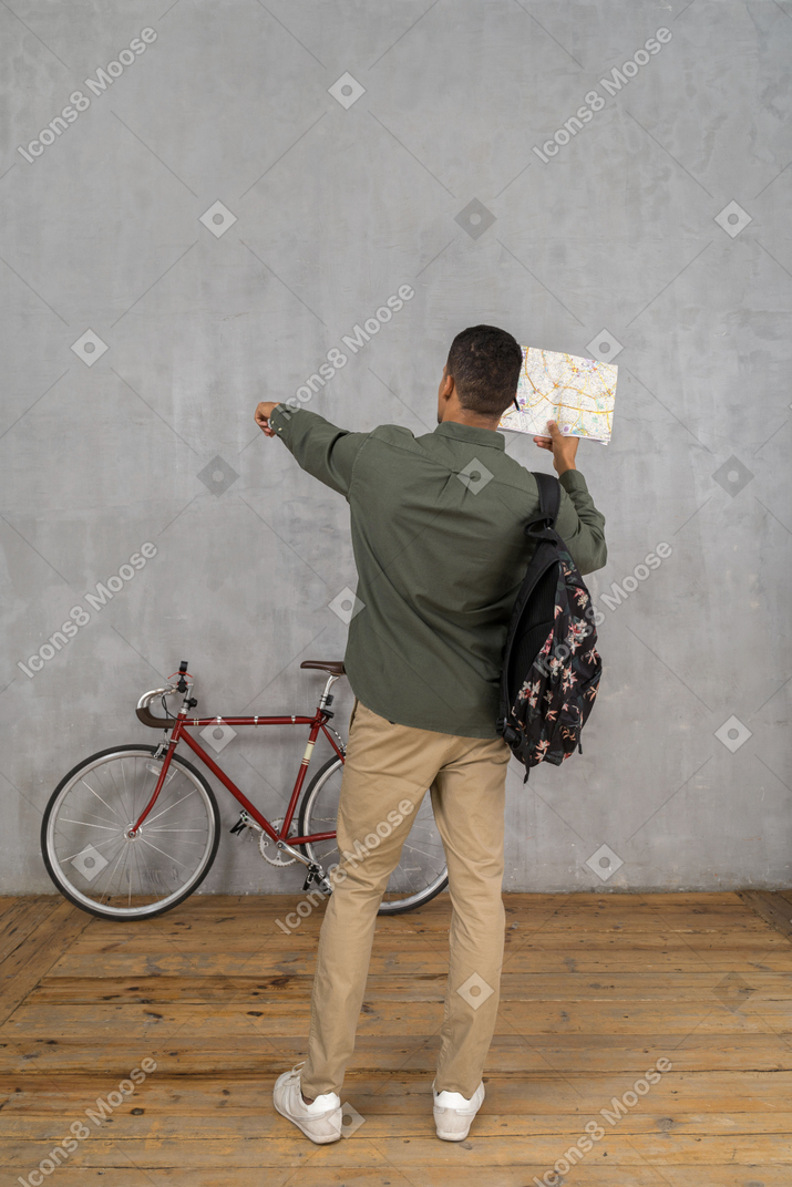Vista traseira de um homem com uma mochila e um mapa mostrando as direções